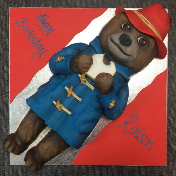Bespoke Paddington-themed cake with fondant bear and red hat, decorated for celebration in Solihull, West Midlands.