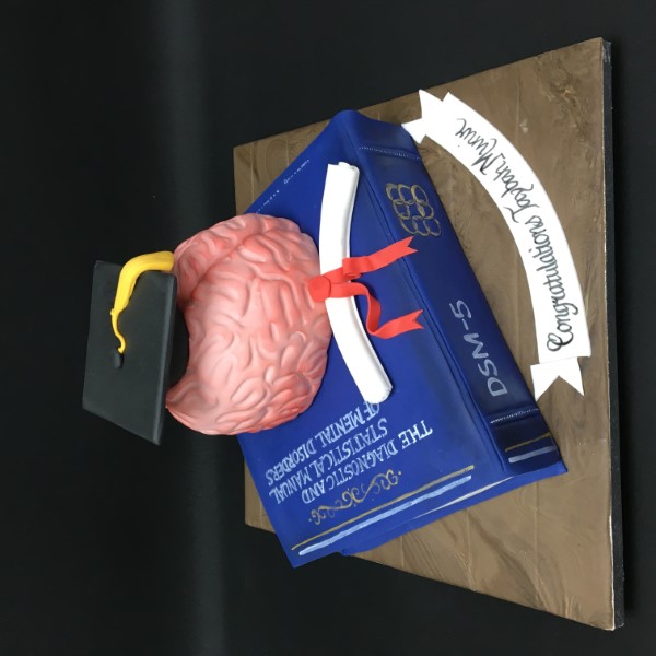 A creative graduation cake featuring a brain, mortarboard, and book design. Perfect for celebrating academic achievements.