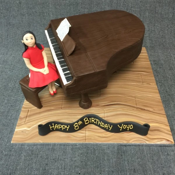 Elegant grand piano cake with a pianist figurine on top, perfect for music lovers and special occasions. Intricate design and attention to detail.