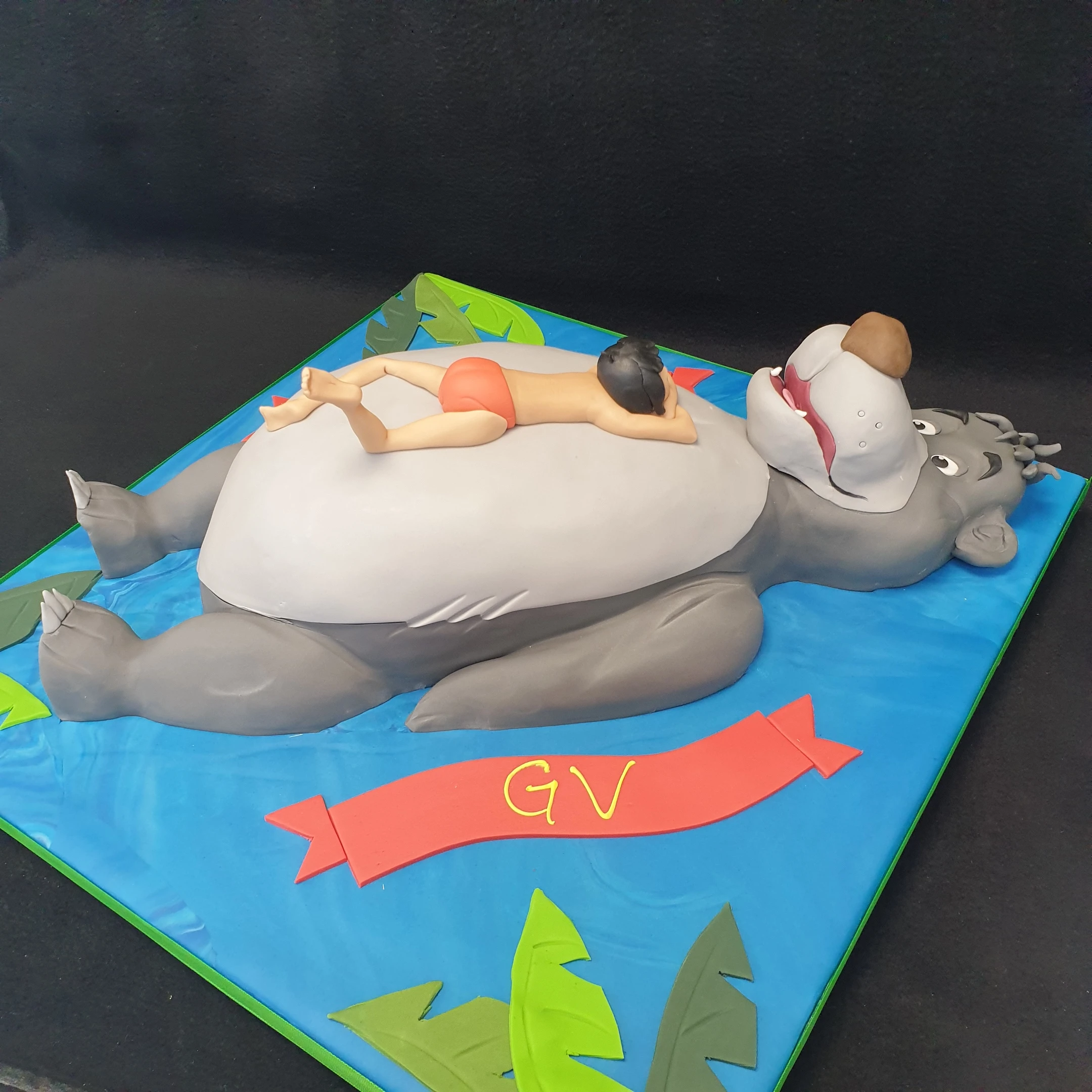 Bespoke Jungle Book celebration cake featuring Baloo and Mowgli figures, decorated with jungle leaves, Solihull, West Midlands.