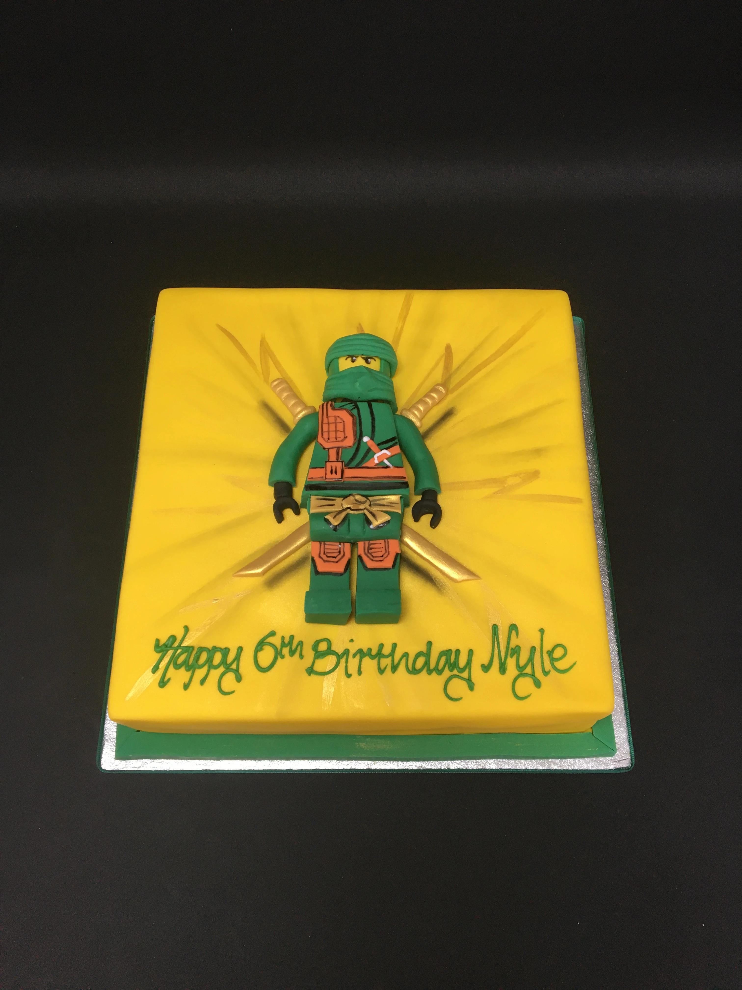 Colourful LEGO Ninjago themed birthday cake with edible toy figures, perfect for fans of the popular toy and TV series. Ideal for celebratory occasions.