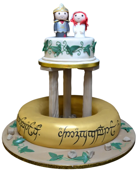 Two-tier wedding cake with sugar paste vines, gold accents, and whimsical figurines.
