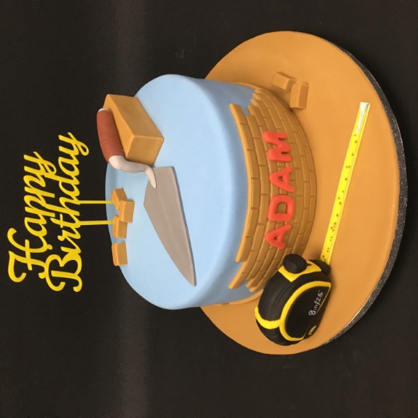 Bespoke celebration cake shaped like bricks and tools, crafted with detailed icing in Solihull, West Midlands.