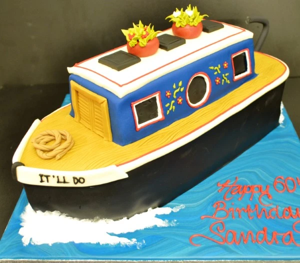 A beautifully designed and intricately detailed canal boat themed cake, perfect for nautical-themed events.