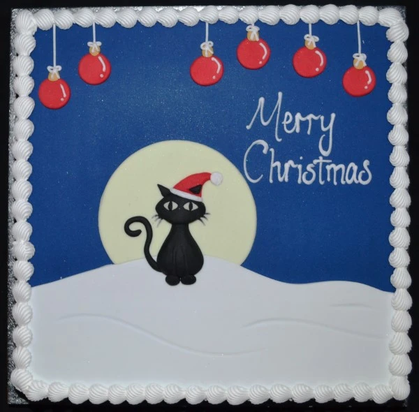A festive cat-themed Christmas cake featuring a snowy winter scene with a playful feline design, perfect for holiday celebrations.