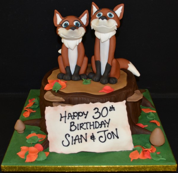 Bespoke cake featuring detailed foxes on a textured tree stump, crafted for a celebration in Solihull, West Midlands.