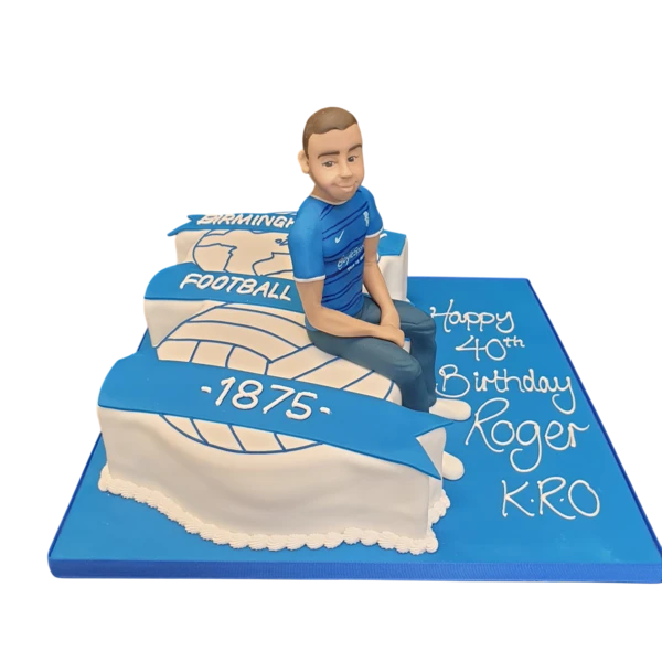 A football-themed cake featuring a figurine of a player atop the Birmingham City FC badge. Perfect for fans of the club or football enthusiasts.