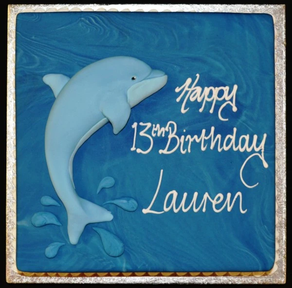 Bespoke square cake with a detailed dolphin topper, decorated for celebration in Solihull, West Midlands.