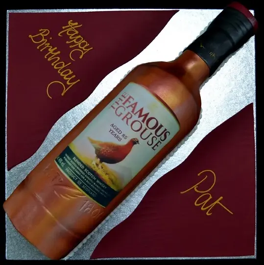 Bespoke cake shaped like a Famous Grouse whisky bottle with detailed label, crafted in Solihull, West Midlands.