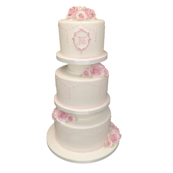 Four-tier wedding cake with pink roses, white sugar paste, and intricate piping.