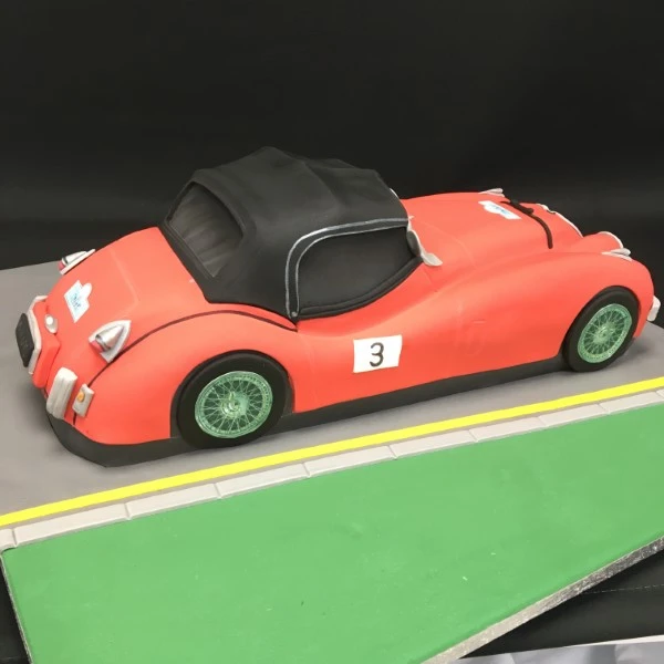 Bespoke Jaguar XK120 cake with detailed silver car design, displayed on a celebration table in Solihull, West Midlands.