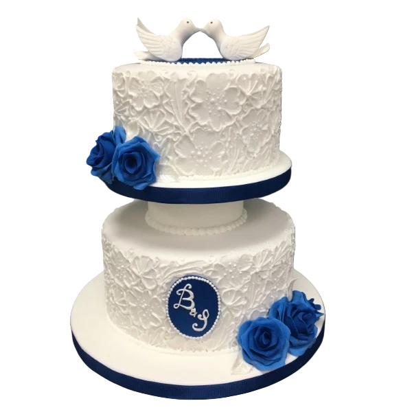Two-tier white wedding cake with royal blue roses and white doves on top.