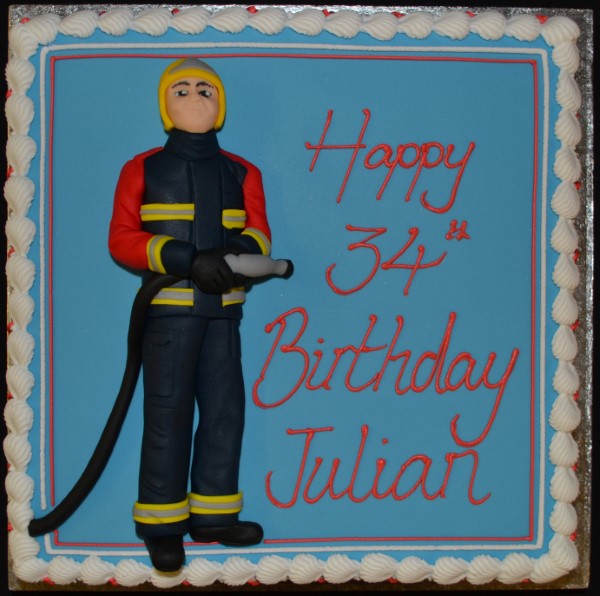 Bespoke cake featuring a fireman holding a hose, decorated with flames, crafted in Solihull, West Midlands.