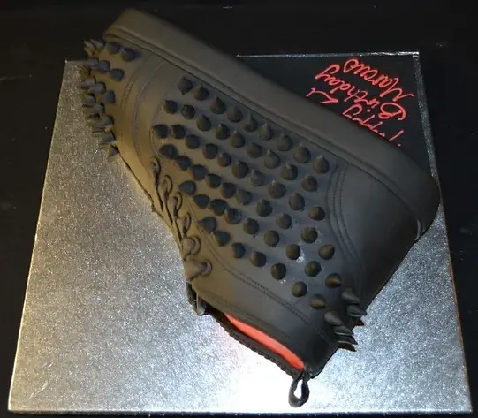 Bespoke cake shaped like a red Louboutin trainer with black sole, displayed in Solihull, West Midlands celebration.