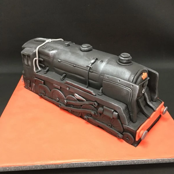 Bespoke steam train cake with detailed wheels and smokestack, crafted for celebration in Solihull, West Midlands.