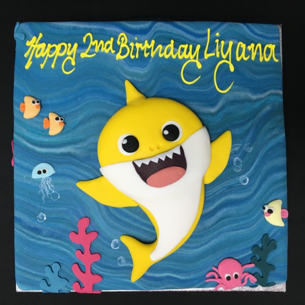 An adorable baby shark-themed cake with colorful decorations and a fun design, perfect for a birthday party or special celebration.