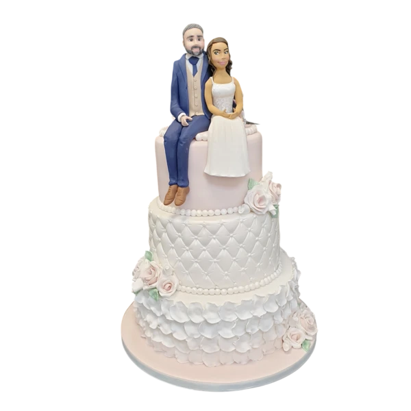 Three-tier wedding cake with sugar paste flowers and elegant couple figurines.
