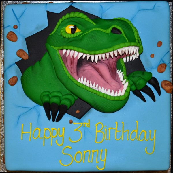 Bespoke square celebration cake featuring a T-Rex dinosaur bursting through, crafted in Solihull, West Midlands.