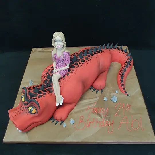 Bespoke cake featuring a girl riding a green dinosaur, decorated with trees, for celebration in Solihull, West Midlands.