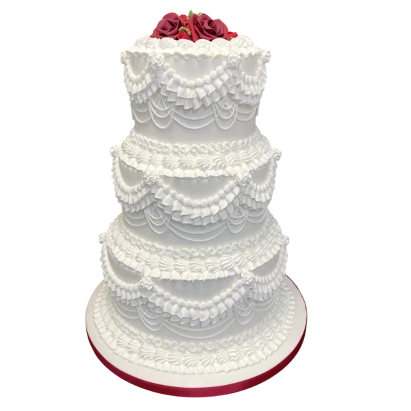 Four-tiered white wedding cake with sugar paste drapery and red roses on top.
