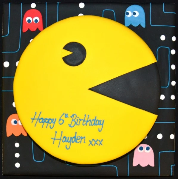 A colourful and playful Pacman-themed cake featuring edible game characters and decorations, perfect for retro gaming fans.