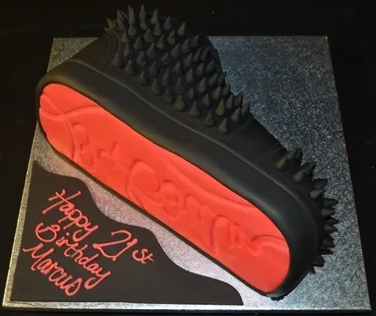 Bespoke cake shaped like a red Louboutin shoe box with black logo, crafted for celebration in Solihull, West Midlands.