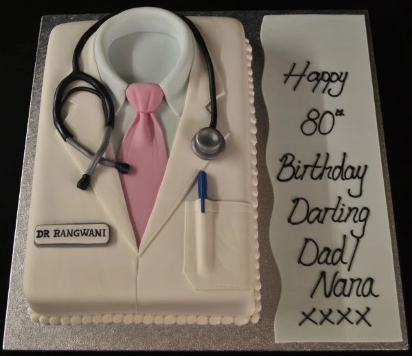 Bespoke cake shaped like a doctor's white coat with buttons and pocket details, crafted in Solihull, West Midlands.