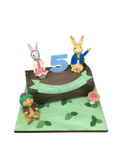 Bespoke celebration cake featuring Peter Rabbit and friends on a log, crafted in Solihull, West Midlands.