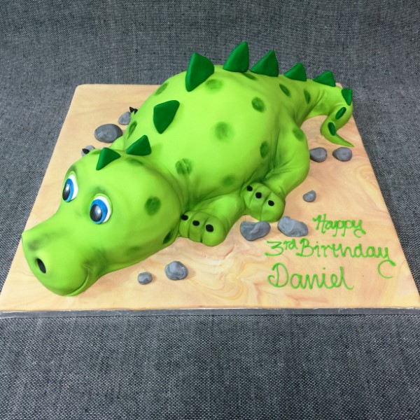 Bespoke cute dinosaur cake with green icing and colorful spikes, perfect for celebration in Solihull, West Midlands.