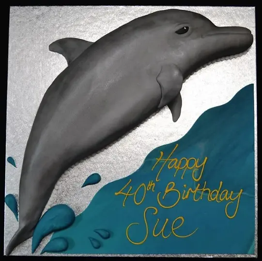 Bespoke dolphin-shaped cake with blue waves and sea details, crafted in Solihull, West Midlands for celebration.