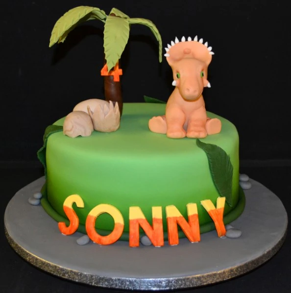 Adorable baby dinosaur-themed cake with a palm tree perfect for a fun and unique celebration, great for dinosaur lovers and themed parties.