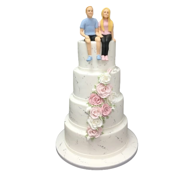 Four-tier wedding cake with sugar paste roses and couple figurines on top.