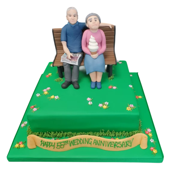 Bespoke cake featuring a husband and wife figurine sitting on a bench, crafted in Solihull, West Midlands.