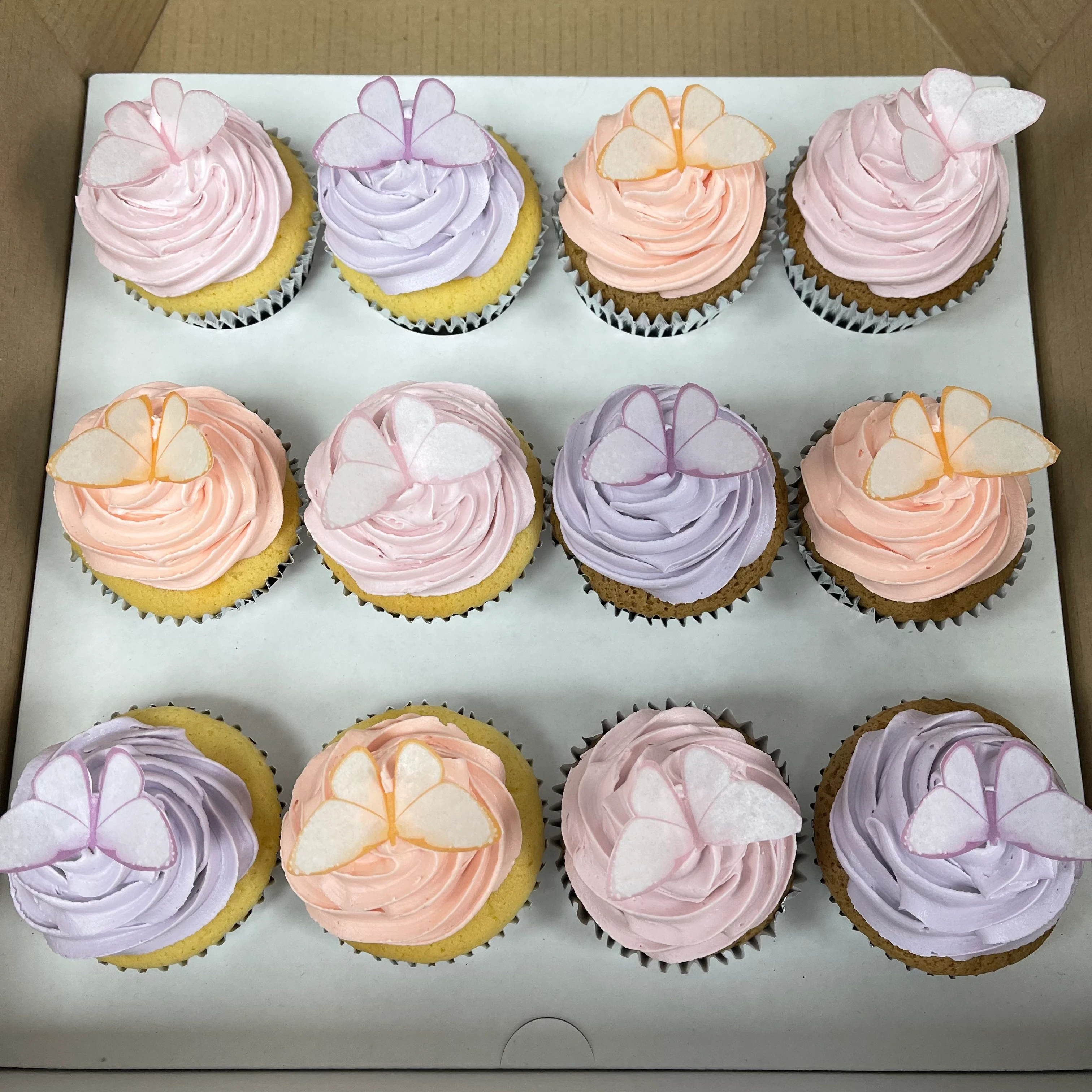 Beautifully decorated pink and purple butterfly cupcakes on a white plate, perfect for a special occasion or celebration.