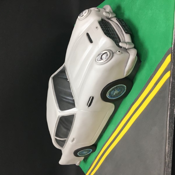 Luxurious Aston Martin DB5 cake model on a silver platter. Perfect for car enthusiasts and special occasions. Handcrafted with intricate details.