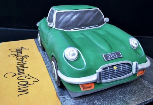 An intricately designed car-shaped cake inspired by the classic Jaguar E Type model, perfect for car enthusiasts and special occasions.