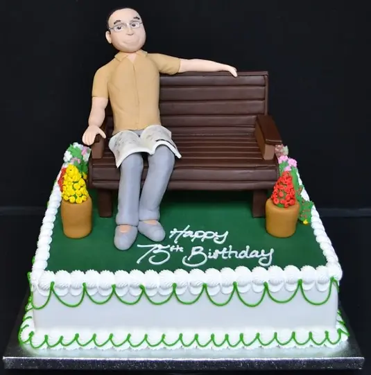 Bespoke cake in Solihull, West Midlands featuring a detailed man sitting on a bench for celebration.