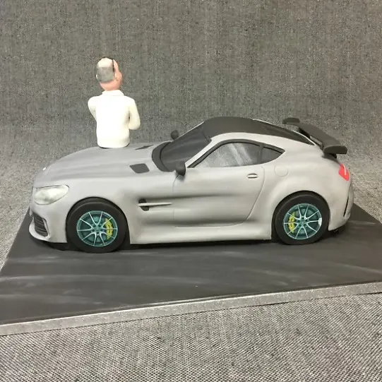 Bespoke cake shaped like a silver MERC AMG GT car, detailed with black wheels, displayed in Solihull, West Midlands.