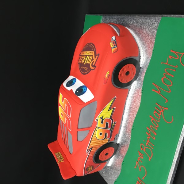 Bespoke Lightning McQueen celebration cake with red racing car design, detailed wheels, and Solihull, West Midlands.