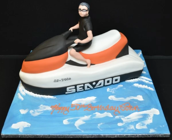 Bespoke jetski-themed cake with blue waves and detailed orange jetski, crafted in Solihull, West Midlands.