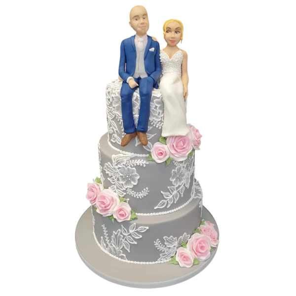 Three-tier grey wedding cake with sugar paste pink roses and figurines on top.