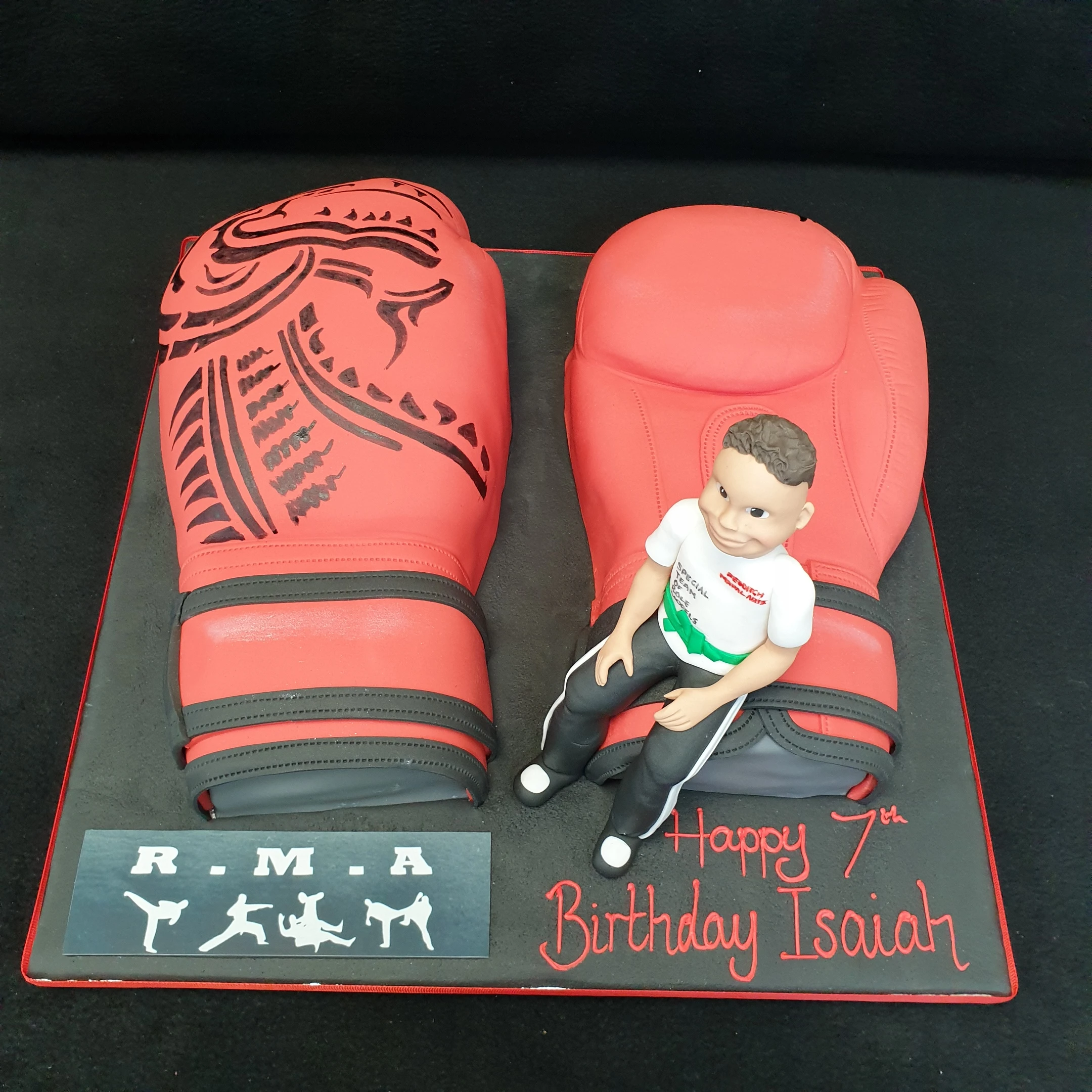 Bespoke cake featuring kickboxing gloves and a little warrior figure, crafted for celebration in Solihull, West Midlands.