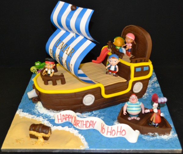 A whimsical pirate ship cake with plastic pirate figures on top for a nautical-themed party in UK.