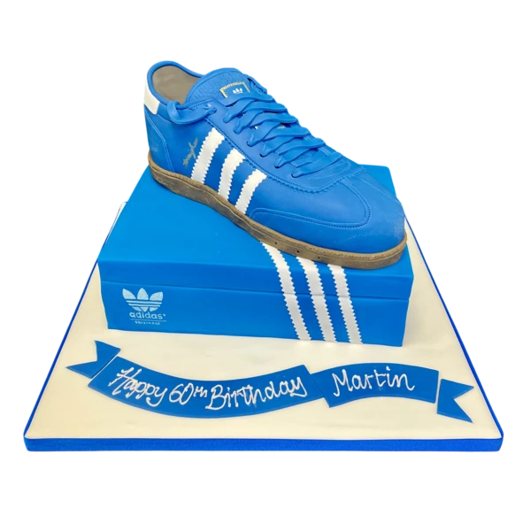 A unique and creative cake design featuring a realistic Adidas trainer on a shoe box, perfect for sneaker fans and sporty celebrations.