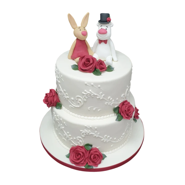 Two-tier wedding cake with red roses, white sugar paste, and whimsical figurines.