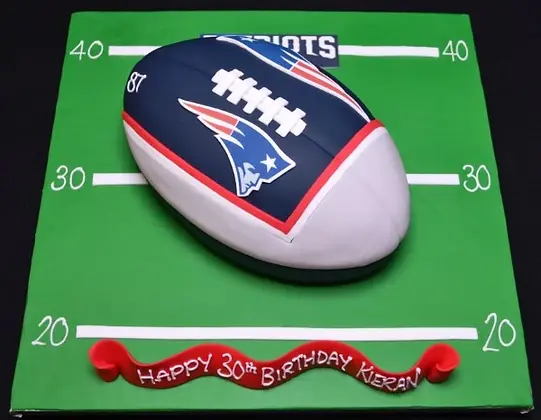Bespoke American football cake with detailed laces and grass effect, perfect for celebration in Solihull, West Midlands.