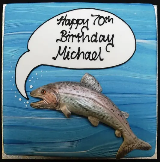 Bespoke cake featuring a colorful fish leaping from blue waves, crafted for a celebration in Solihull, West Midlands.
