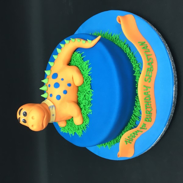 Adorable orange dinosaur shaped cake with colourful decorations perfect for a dinosaur-themed birthday party.