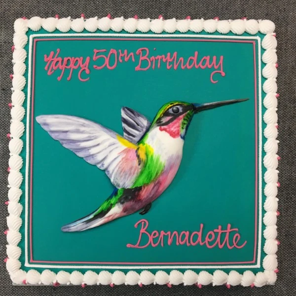 Bespoke hummingbird-themed celebration cake with detailed edible flowers, set in Solihull, West Midlands.
