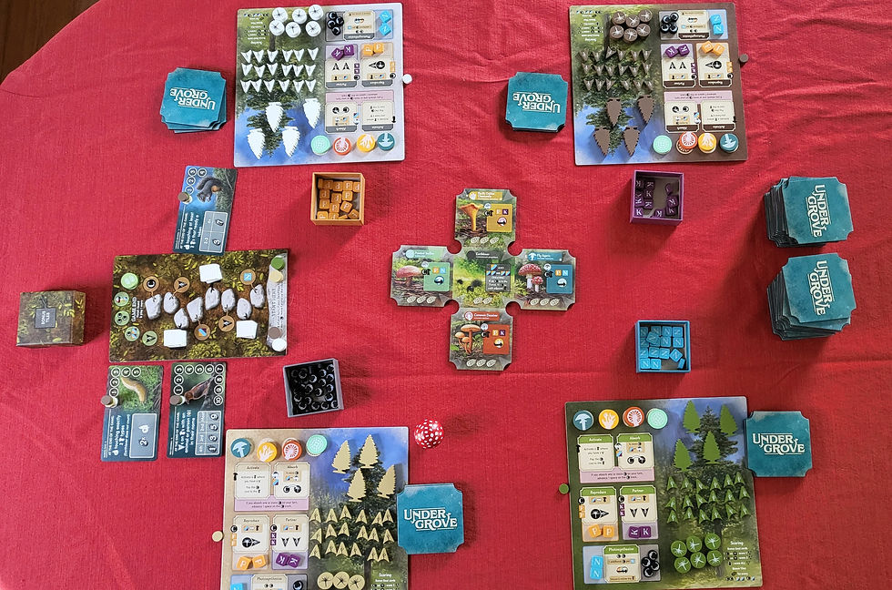 Undergrove set up for four players. At the four corners of the table, each player has a player board with their tokens laid out: saplings, roots, trees, and their starting resources. Each player also has three mushroom tiles facedown as their starting hand. In the center of the board is the starting tile, which is a cross-shaped array of five tiles. Each tile depicts a different mushroom. Other mushroom tiles fit next to these starting tiles to extend the grid. The corners of each tile are cut in so that when four tiles are all placed together, there is a small circle of space between them where a player could place a sapling token. To the left of the central board is the carbon track board, along with a playing piece matching each player's color of tokens. Arrayed around the carbon track board are three animal objectives. One of hte four players starts with the start-player token, which is a hefty wooden mushroom with a red cap and white spots, just like the mushrooms on the box cover.